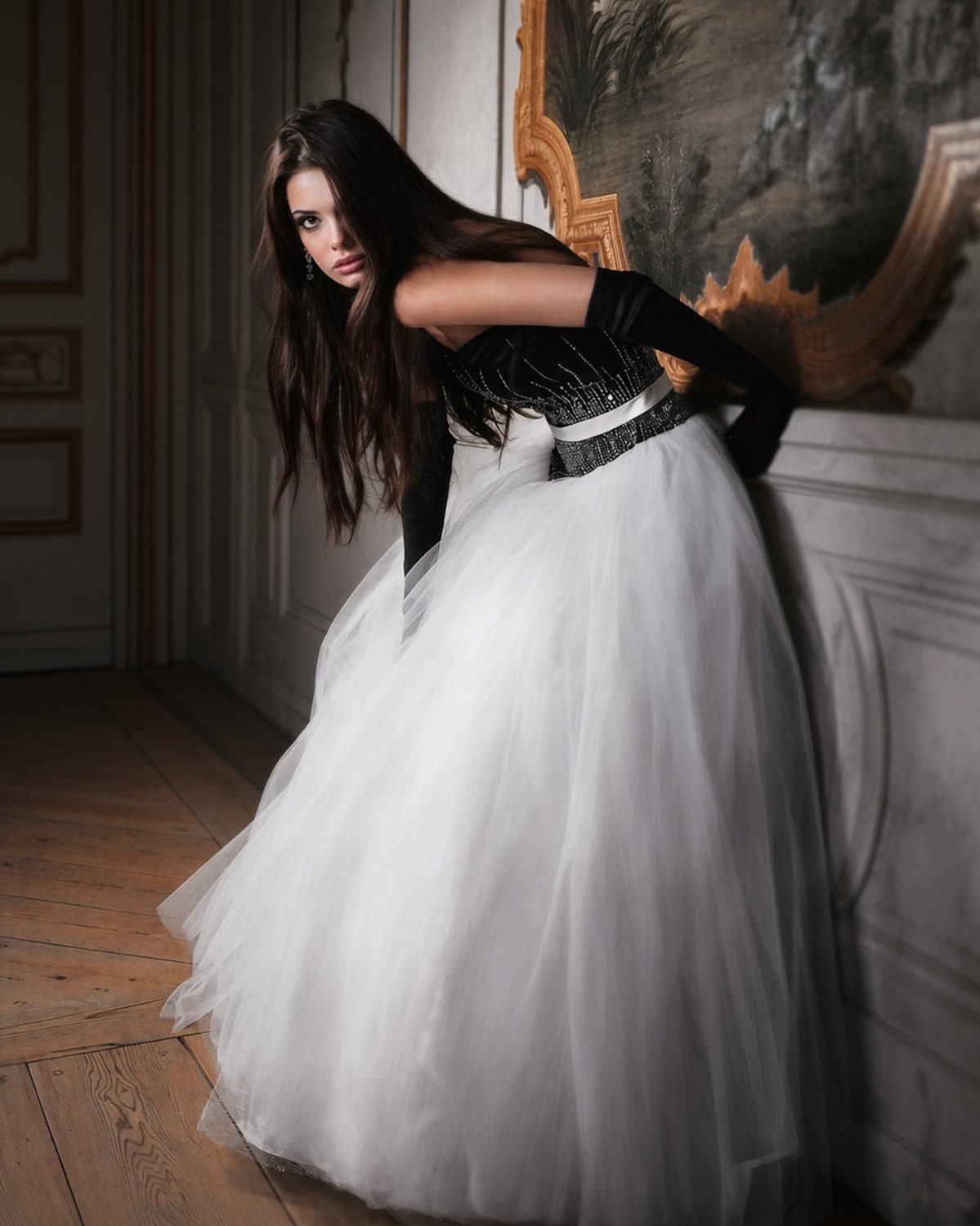 Model in a black and white tulle gown with long dark hair, leaning against a palace wall